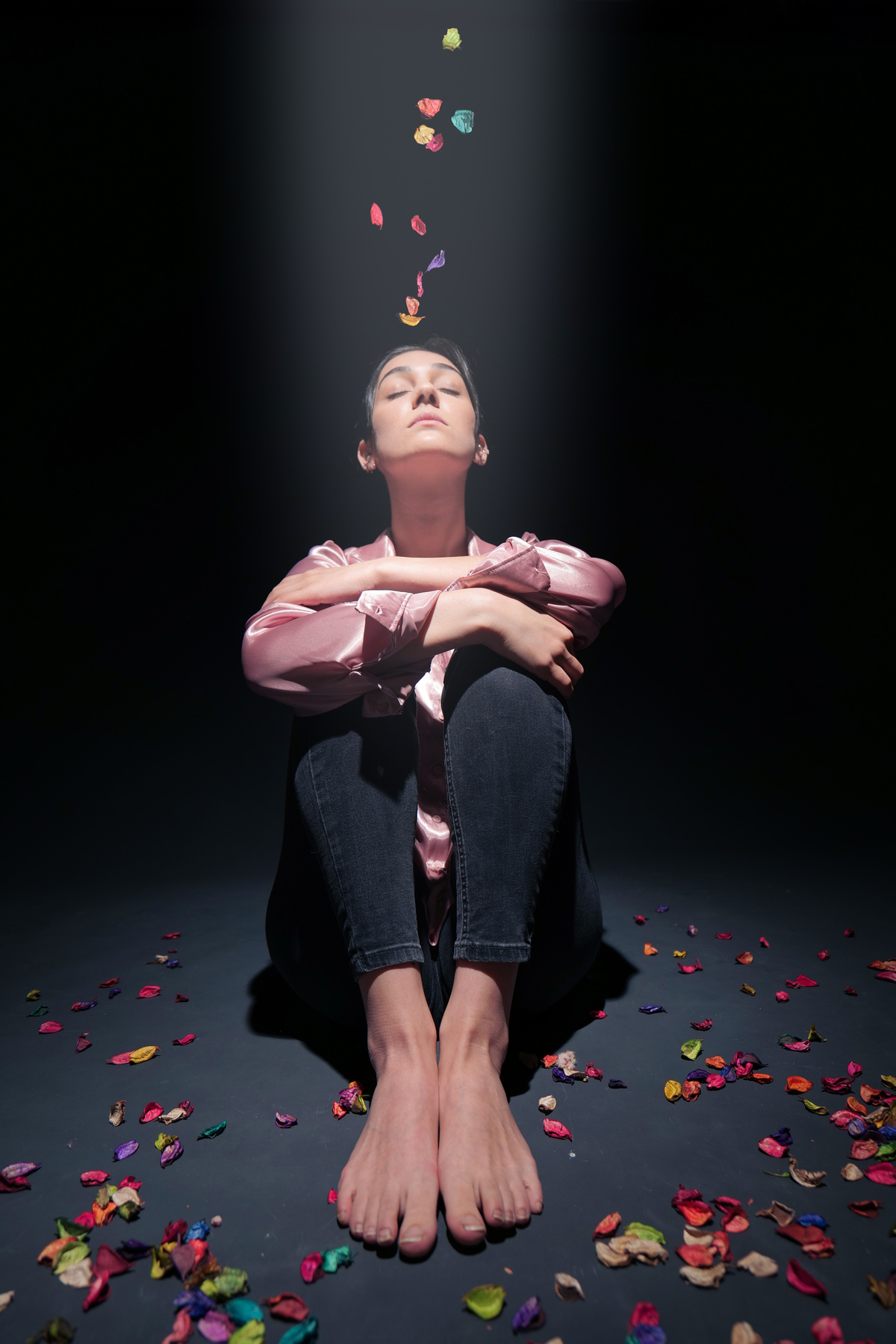 Sitting Woman on Dark Background with Colorful Petals