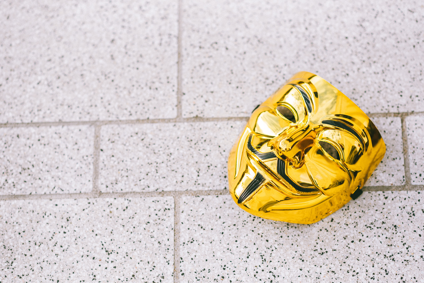 Bright golden anonymous mask on tiled pavement