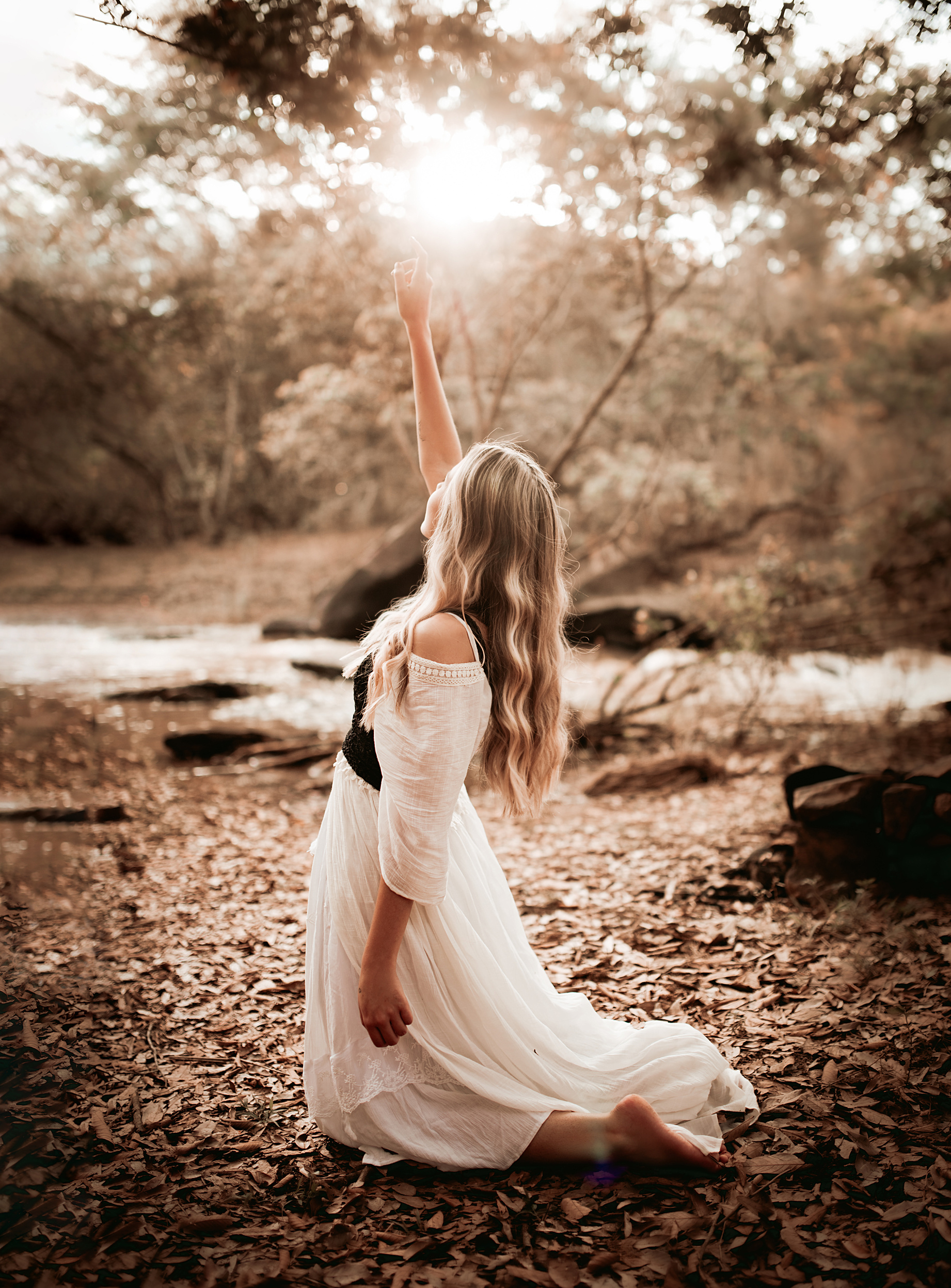 Woman in White Dress Kneeling With Hand Raised