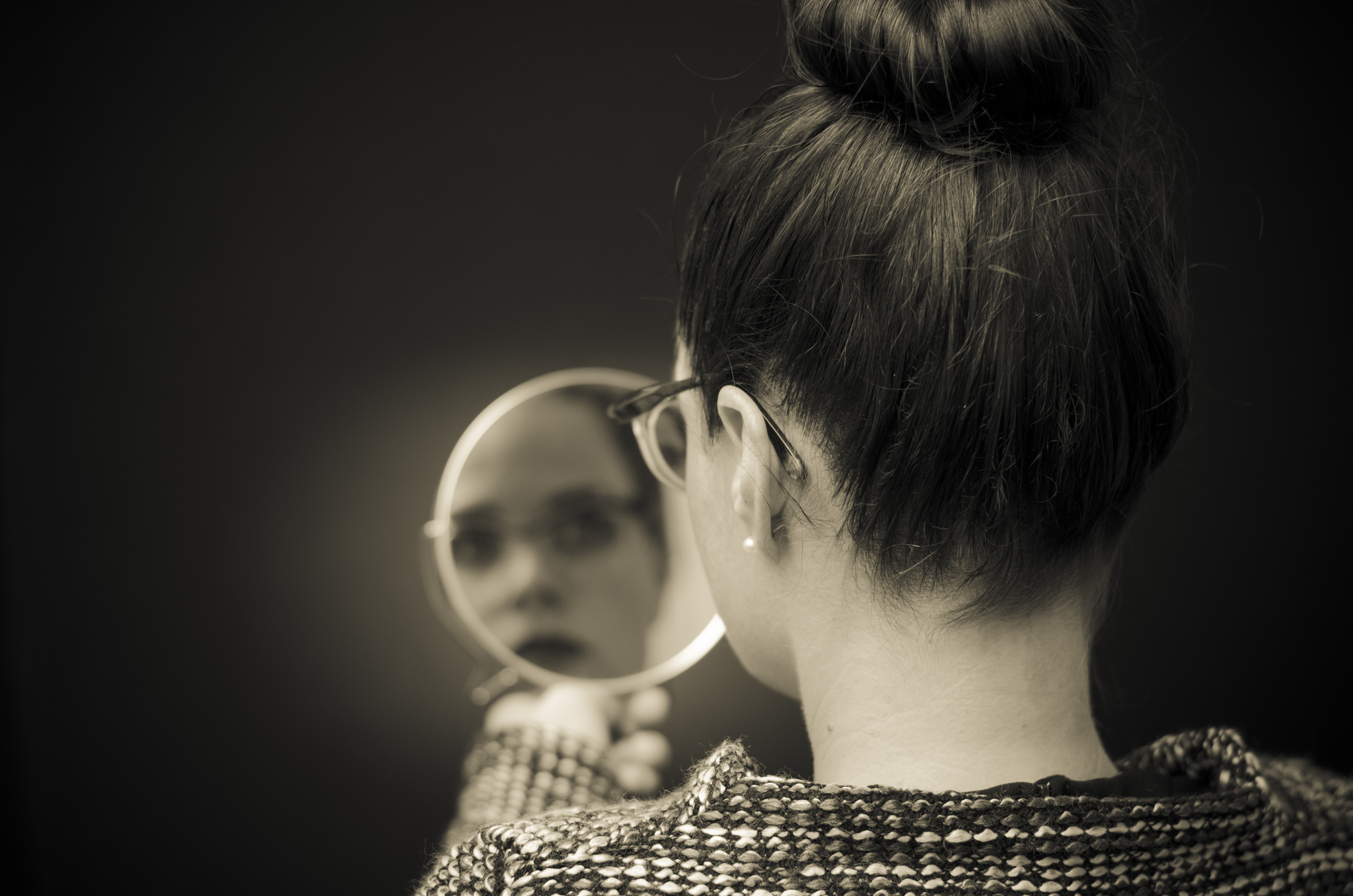 woman looking at self reflection in mirror