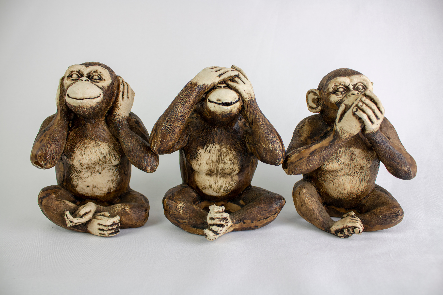 Three Wise Monkeys in a row, Hear no evil, See no evil, Speak no evil, brown monkeys on a white background.