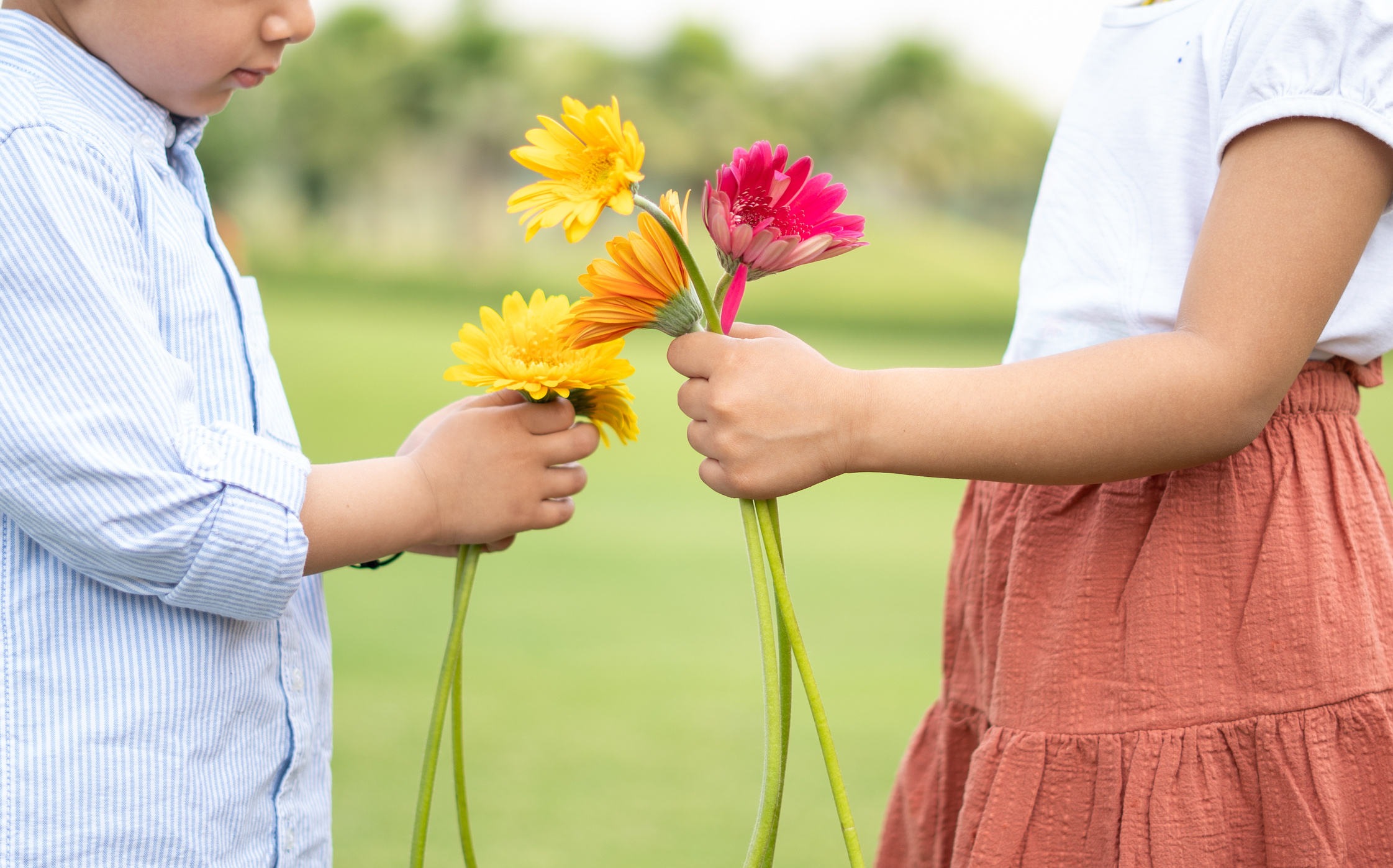 Little Girl and Boy Holding Flowers Outdoors