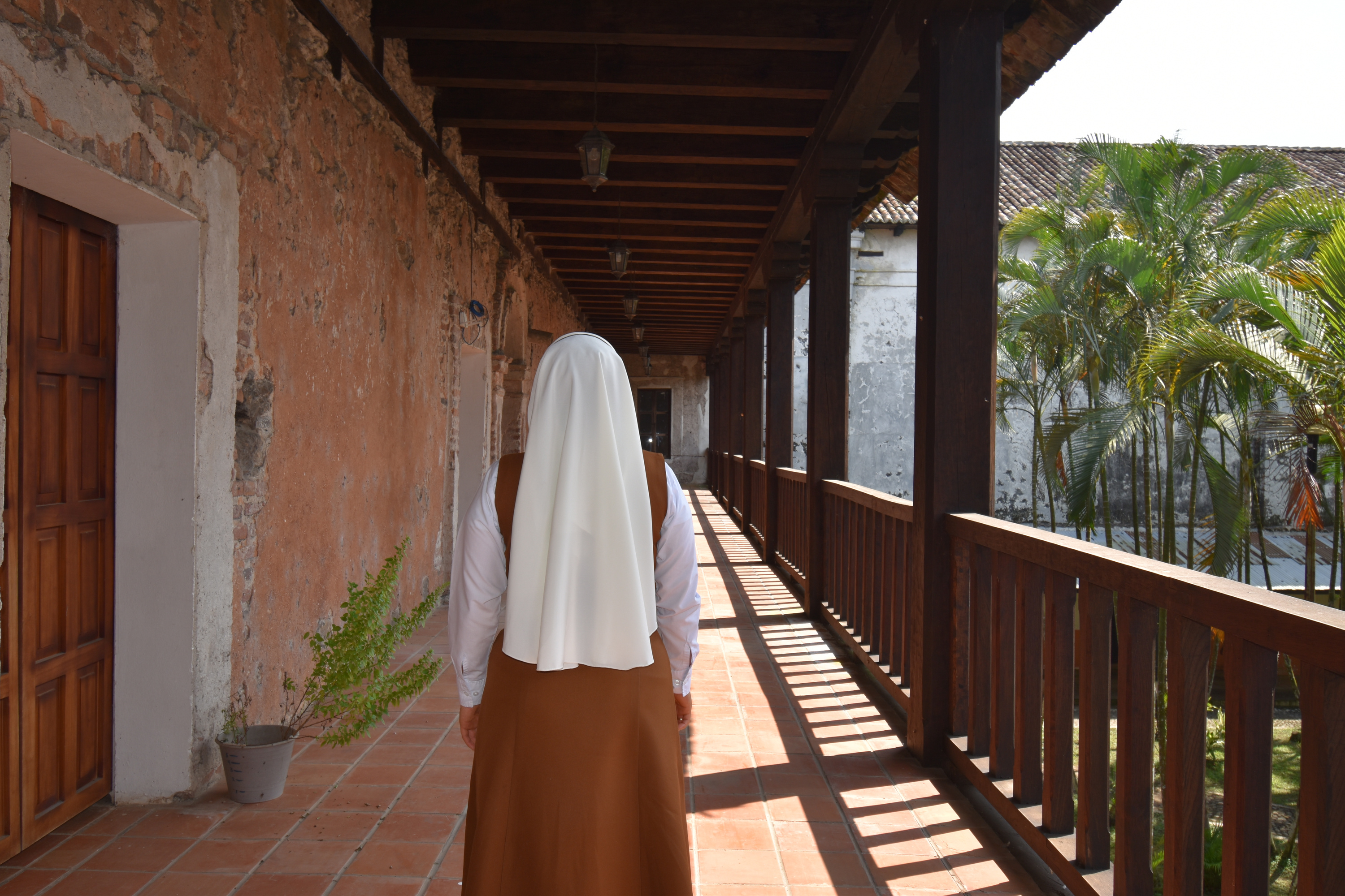 Back View of a Nun Standing in a Balcony Hallway