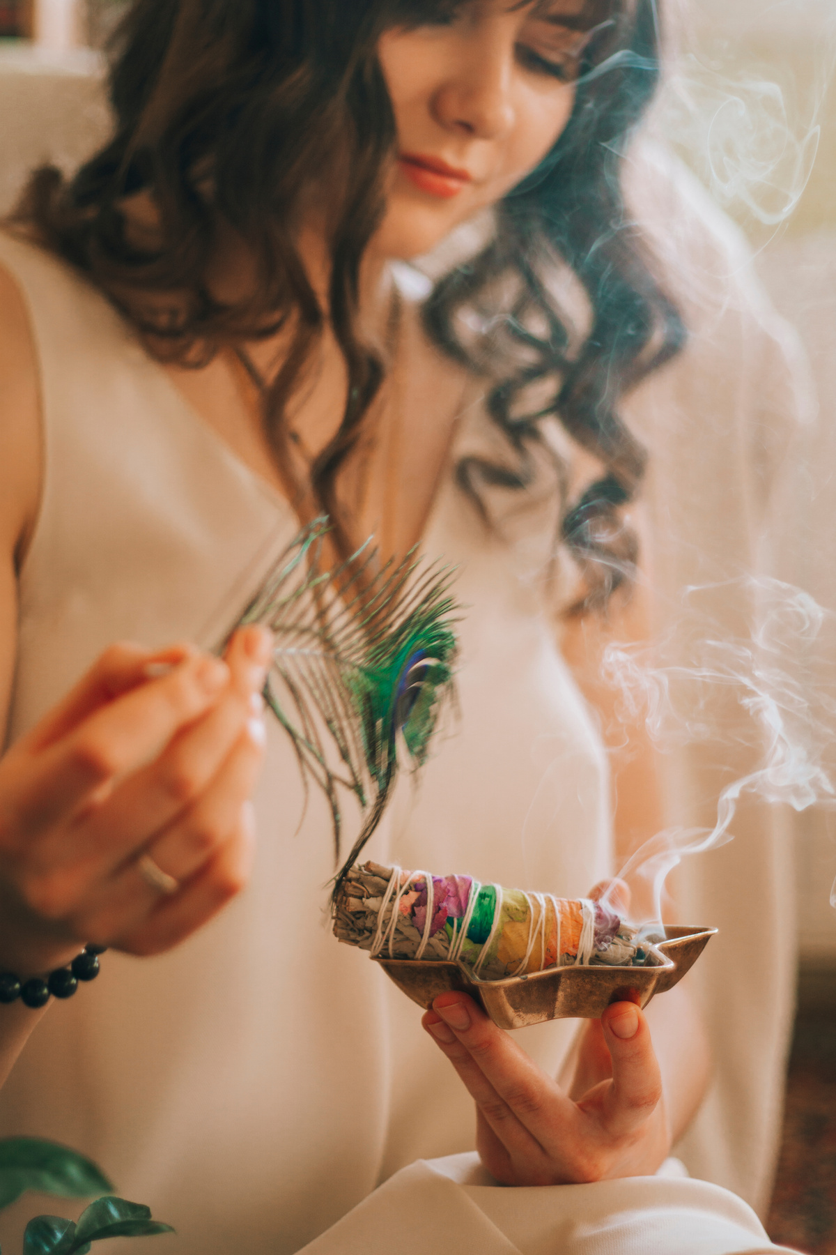 Woman with burning smudge sticks and peacock bright feather