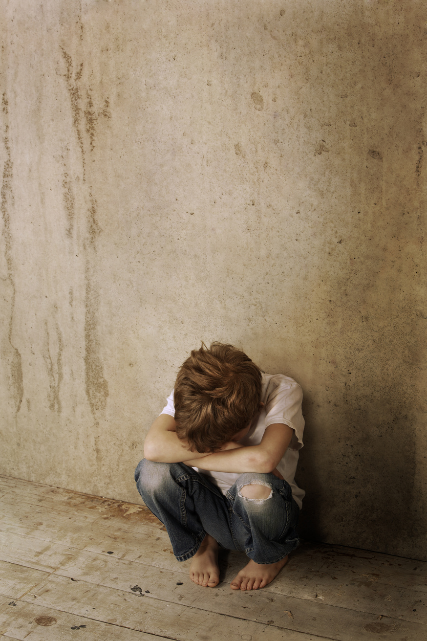 Child kneeling against wall