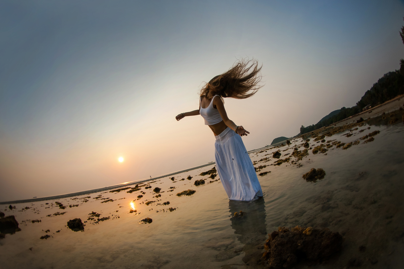 beautiful woman is dancing on the beach at sunset